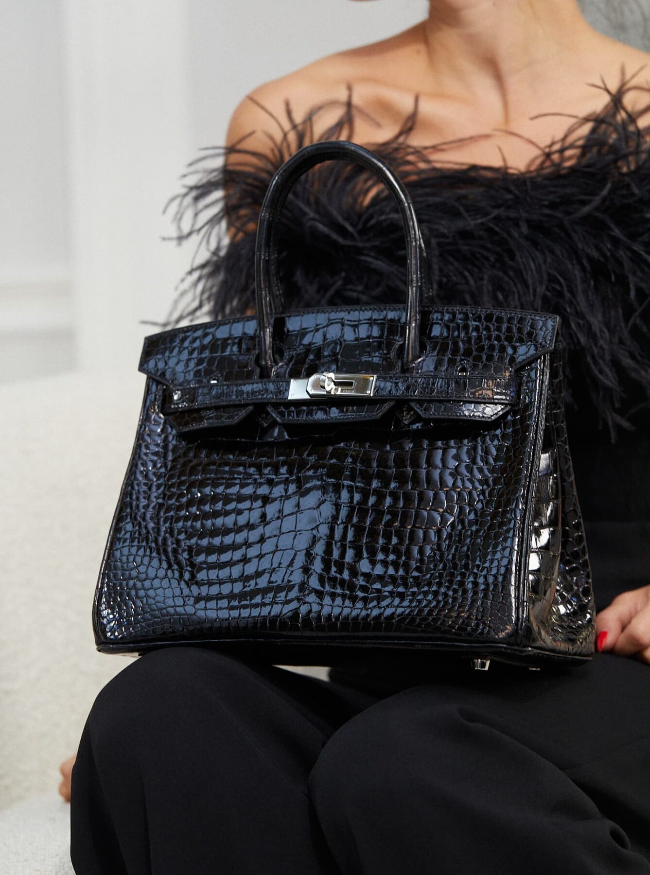 A black crocodile Hermès Birkin held in the hand