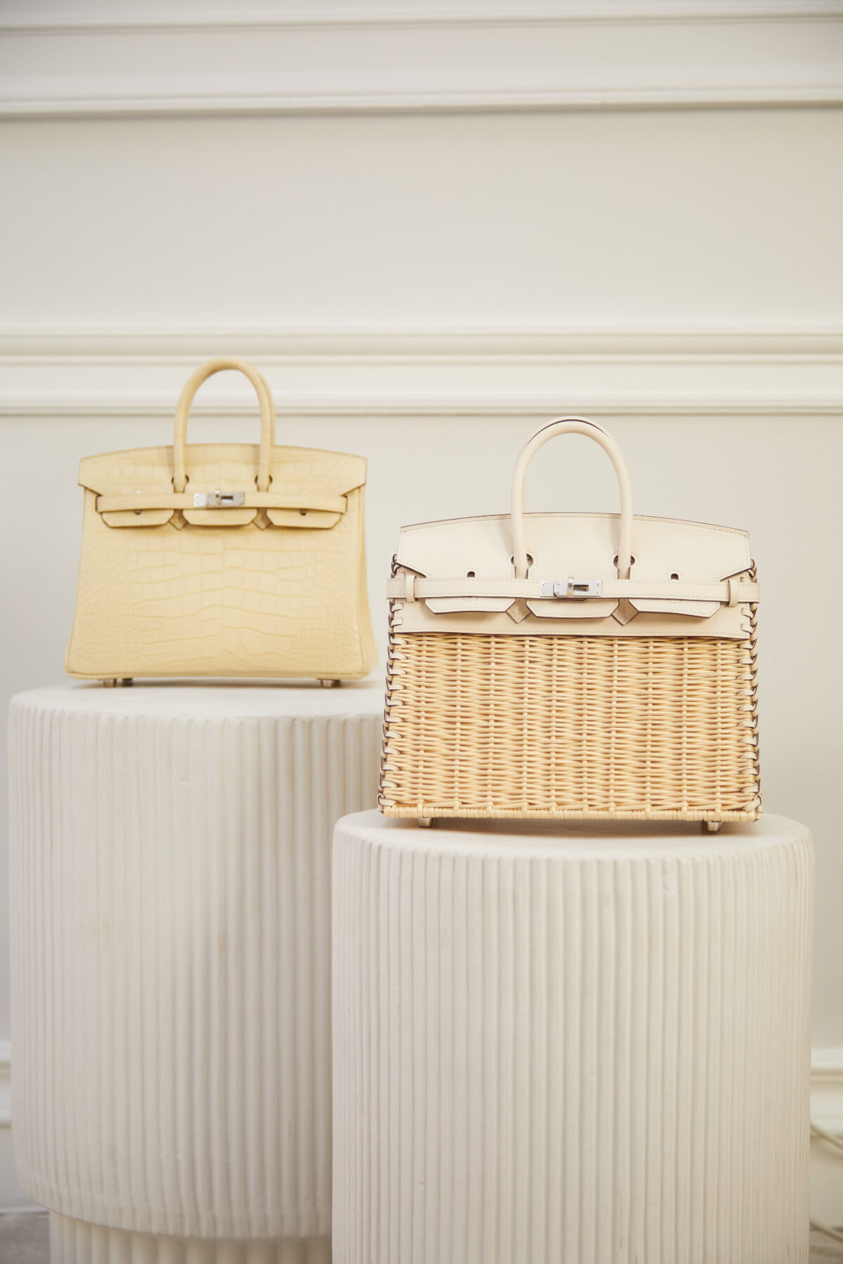 Two Hermès bags displayed on fluted pedestals
